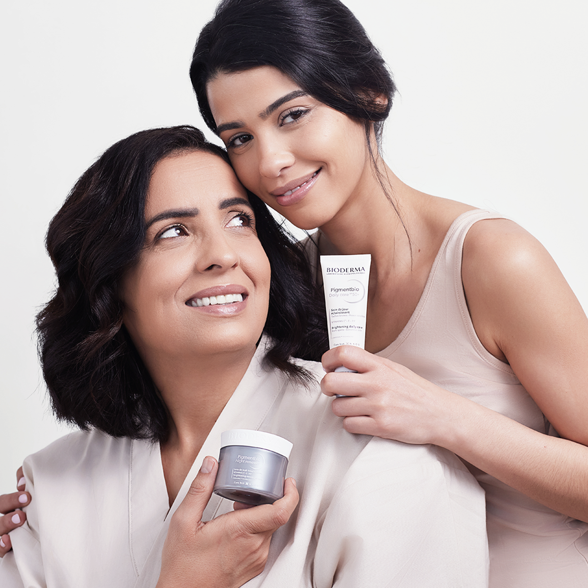 Dos mujeres usando productos Pigmentbio de BIODERMA para tratar manchas faciales.